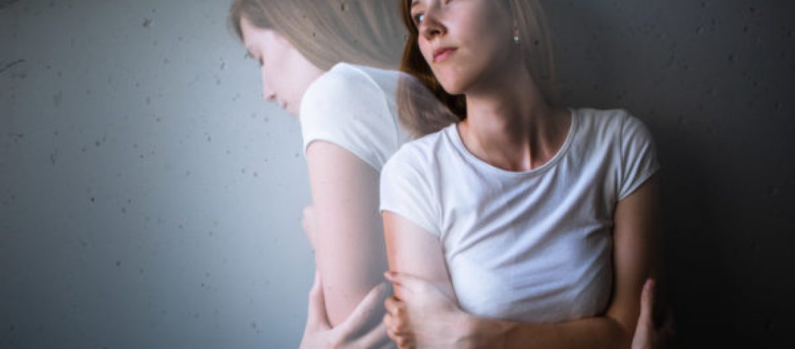 Young woman suffering from a severe depression/anxiety (color toned image; double exposure technique is used to convey the mood of unease, progression of the anxiety/depression)